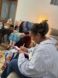 an elderly woman sitting in a chair looking at a young woman as she takes notes. 