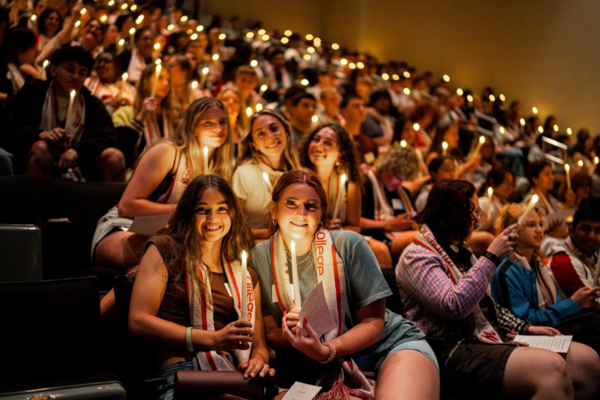 Students hold lit candles in a crowd