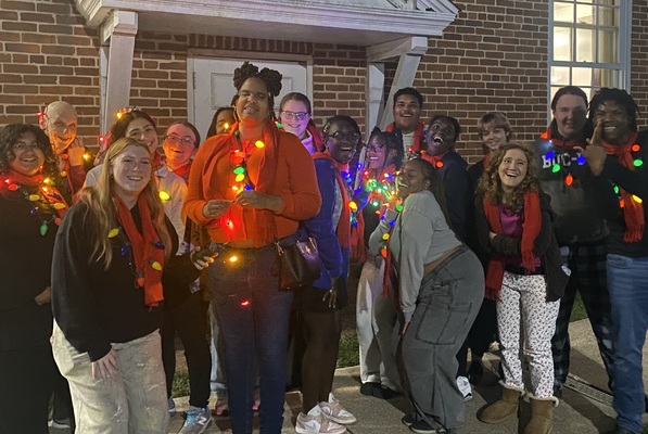 McDaniel College Music faculty members and students smiling for a photo in their holiday gear, including twinkling necklaces. 