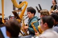 A student plays the saxophone in rehearsal.