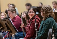 A student smiles while holding her oboe in rehearsal.
