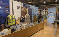 Photo of display case featuring photos and uniforms.