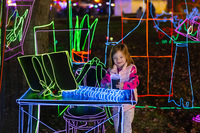 A girl plays in a lit-up scene that looks like a neon cartoon drawing of an office.