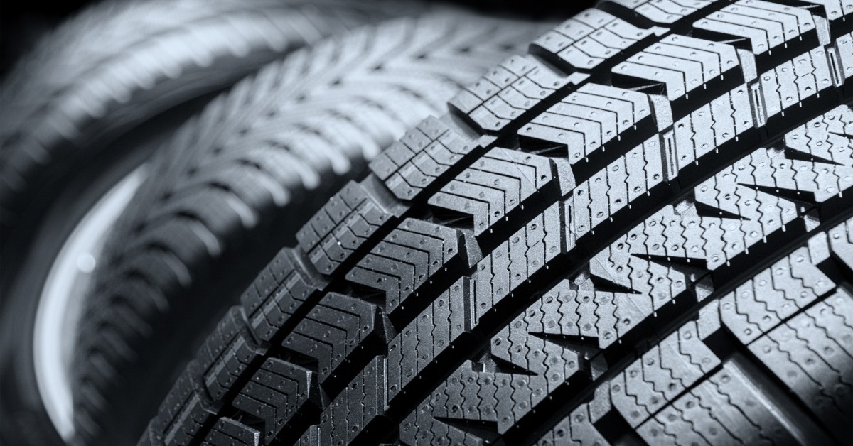 A close-up view of a car tire and its tread design. The tire features asymmetrical tire treads for safety.