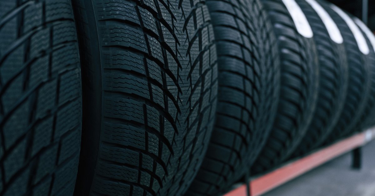Multiple tires with the same tread pattern stacked on a shelf together. They are all new with no dirt or marks on them.
