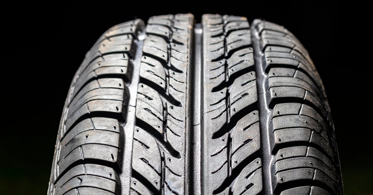 A tire facing forward. The tire is illuminated against a black background to highlight the intricate treads on the tire.