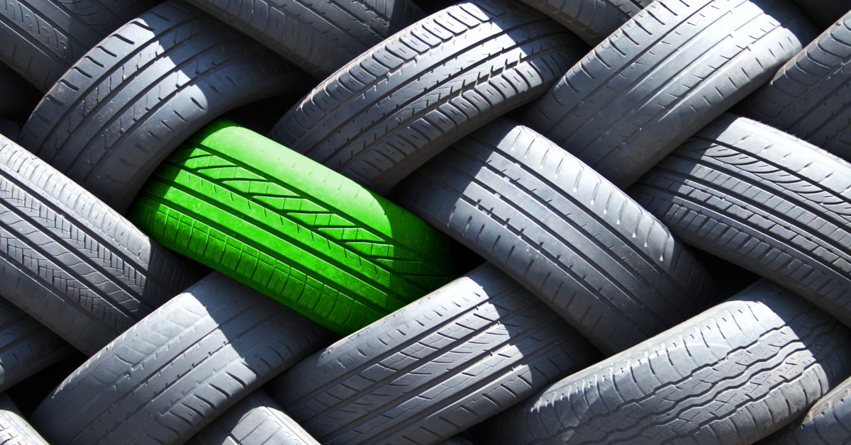 A stack of tires sitting on top of each other. One tire is green, while the others are their normal black color.