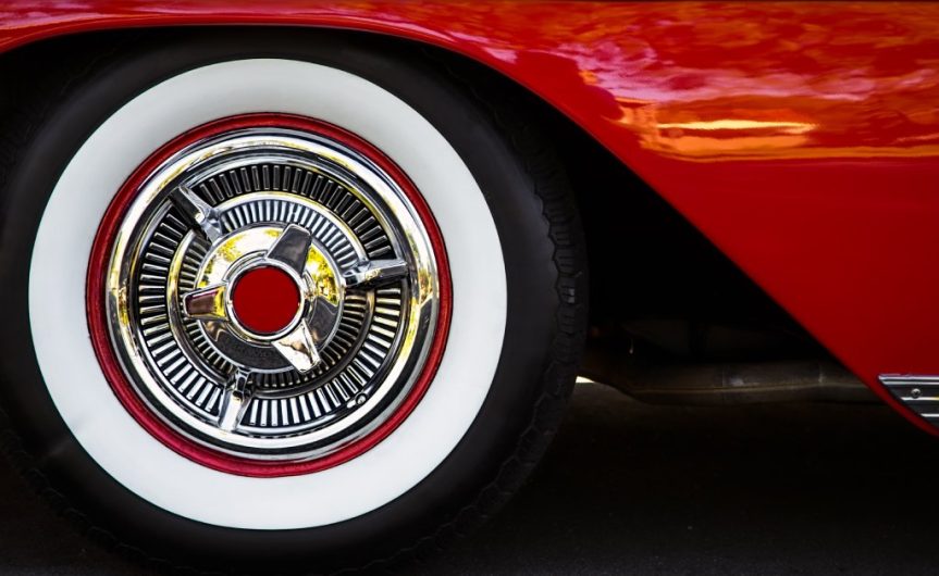 The wheel of a classic-style red vehicle. The tire has a white outline and a red circle at the center.