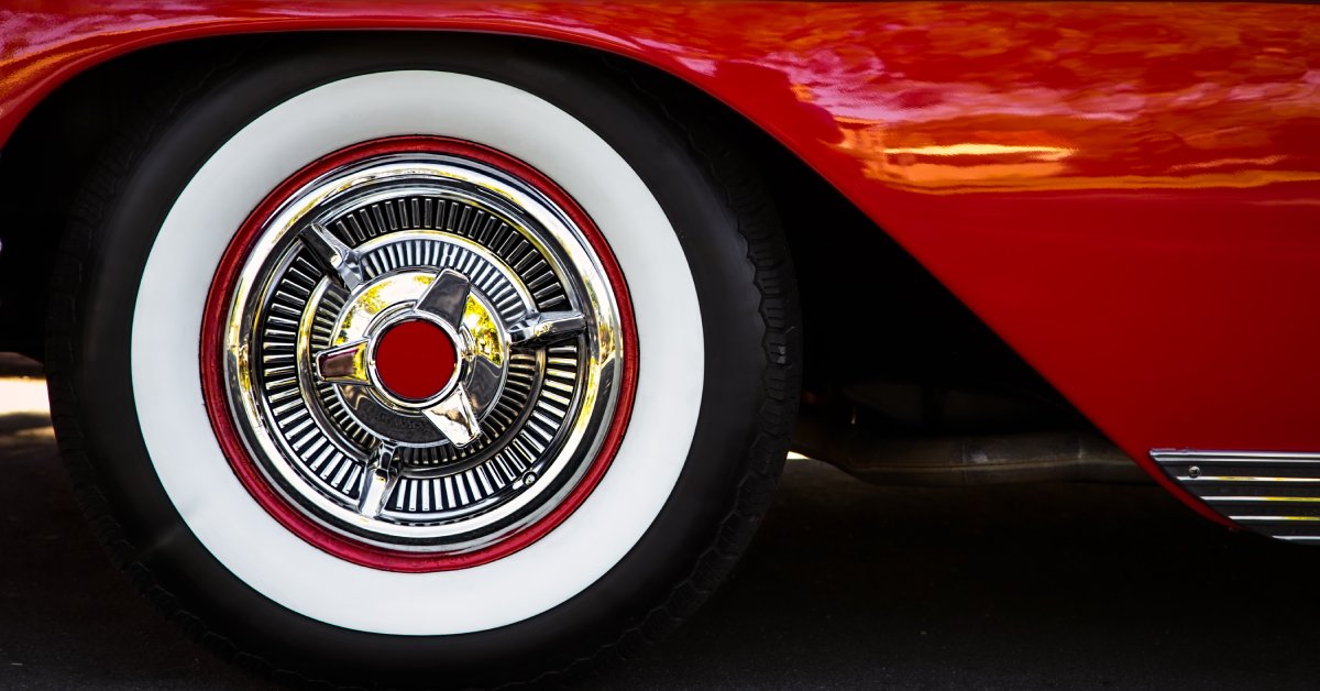 The wheel of a classic-style red vehicle. The tire has a white outline and a red circle at the center.