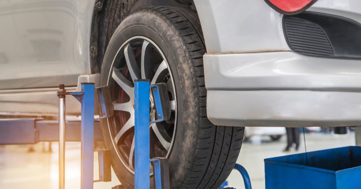 The bottom of a car lifted in the air by a suspension system so that professionals can do maintenance on the vehicle.