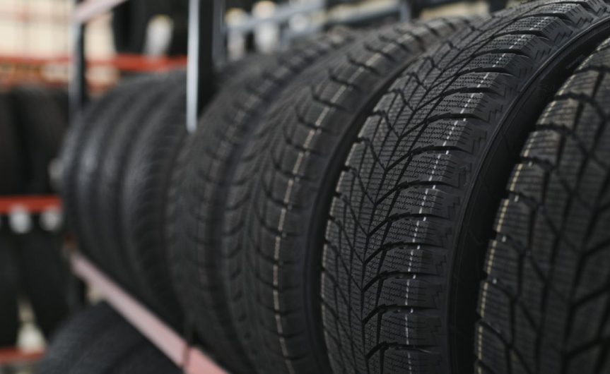 A row of new tires sitting on a storage rack in a tire factory. The tires have a distinct V-shaped tread.