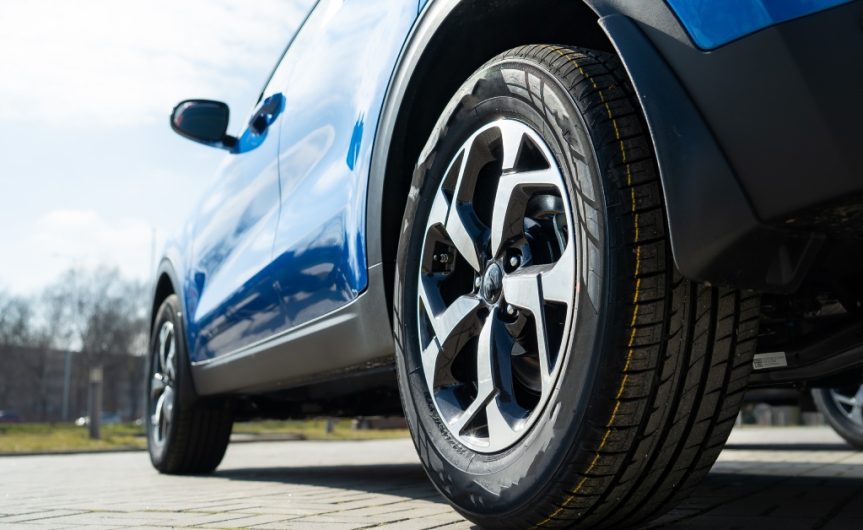 A blue car parked on a clear road. The sunlight is reflecting off the vehicle's exterior, highlighting how clean it is.