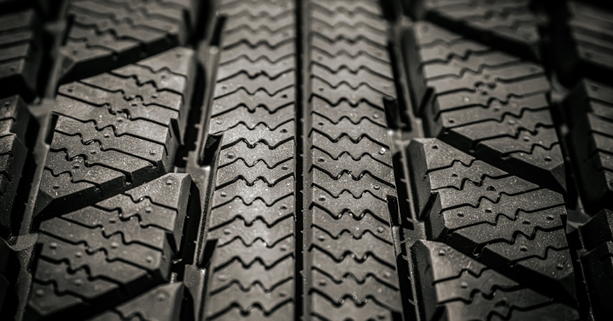 The treads of a winter tire with small zig-zags and an intricate design in the grooves down the side and center.