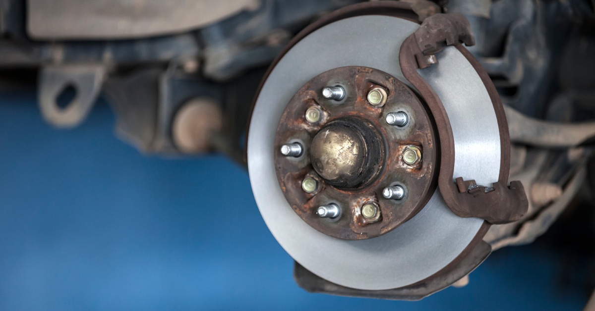A car wheel hub without a wheel or tire attached to it. The hub has bolts and screws sticking out.