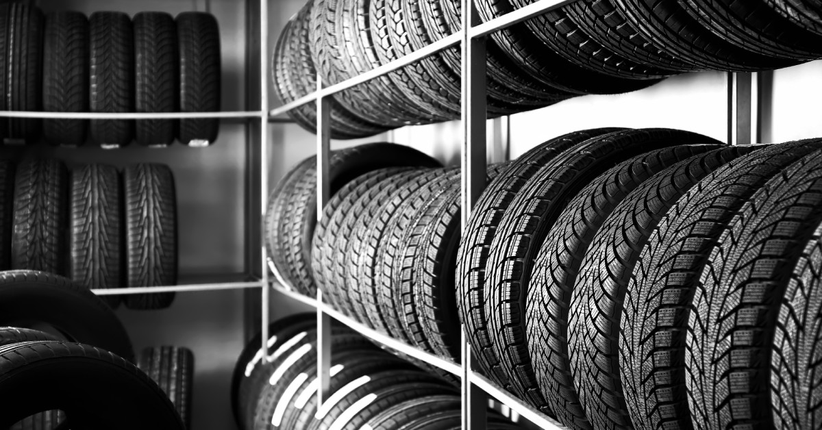 New car tires in an automotive shop stacked on shelves in a storage room. Some of the tires have stickers.