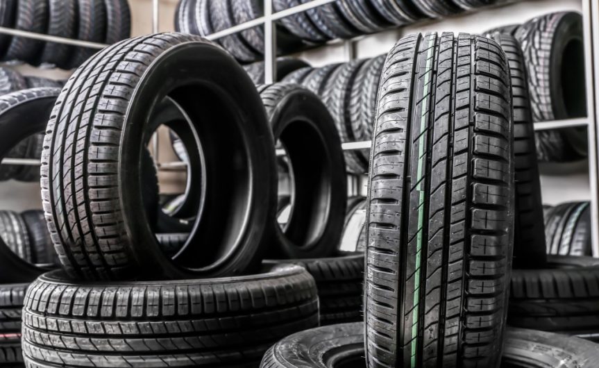 On the wall are shelves of tires, with some tires stacked on the floor. A few tires are upright in the stack.