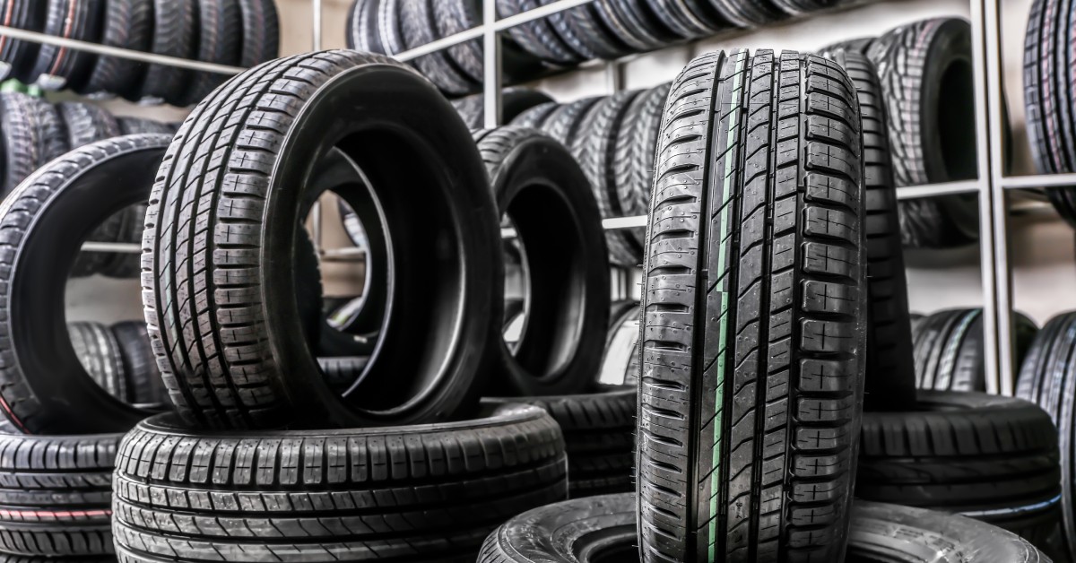 On the wall are shelves of tires, with some tires stacked on the floor. A few tires are upright in the stack.