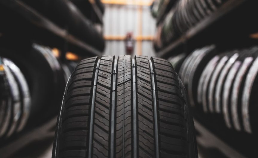 One tire sitting in the center of a tire storage rack with other tires placed on the shelves on each side.