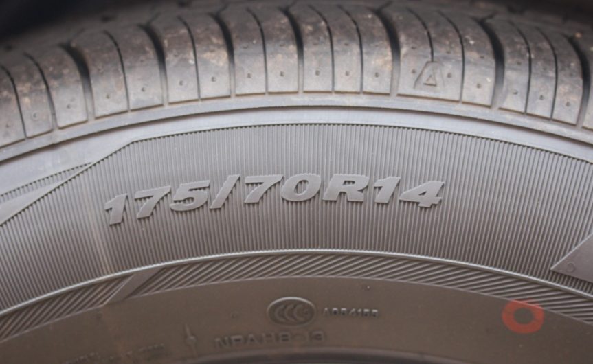 A close-up of the sidewall of a car tire the worn tread and displaying the tire numbers 