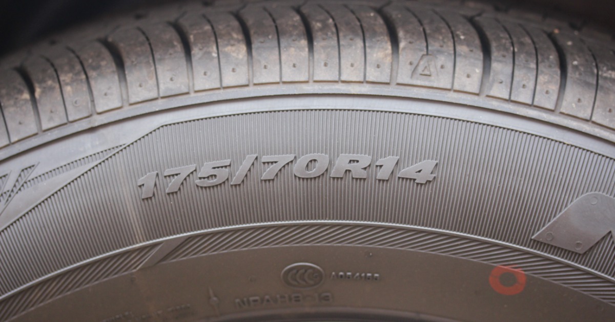 A close-up of the sidewall of a car tire the worn tread and displaying the tire numbers 