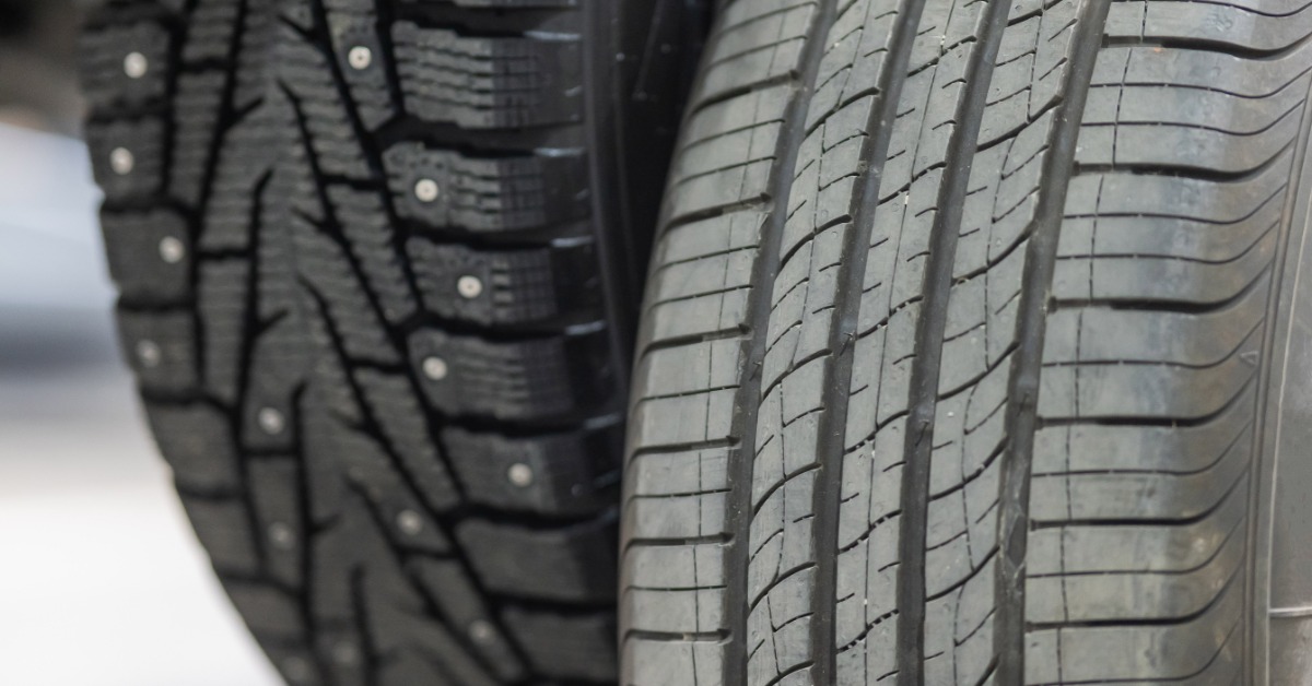 Two tires sitting next to each other. One tire is clean and new, while the other is older and has dust on it.