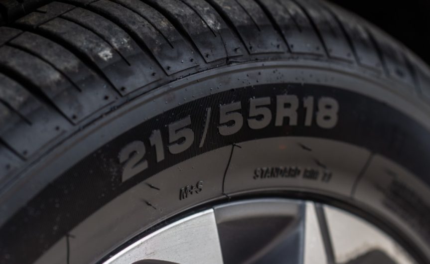A close-up of the sidewall of a car tire with the number sequence displaying tire width, height, and wheel diameter.