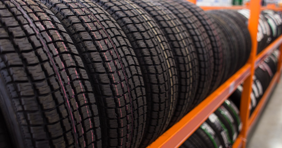 A close-up of a two-level orange rack holding brand-new automotive tires for sale displayed vertically.