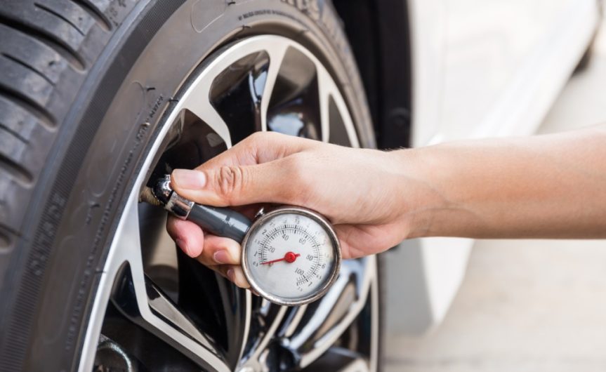 A close-up of someone holding a pressure gauge against the valve of a tire. The gauge is still at zero.
