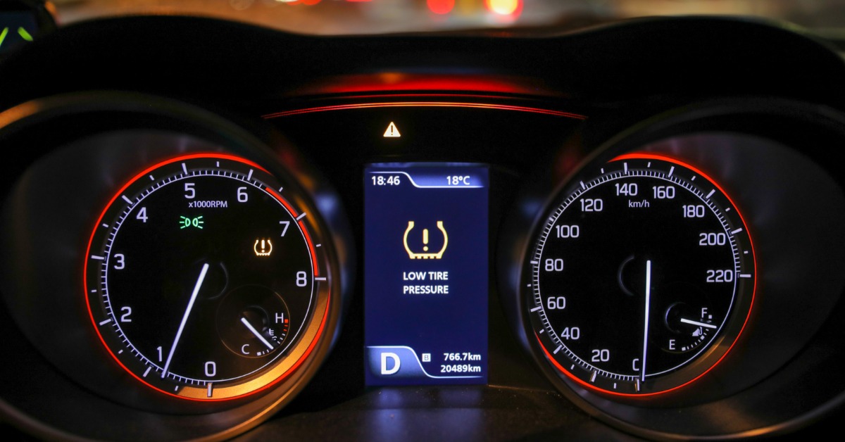 A car's dashboard with the tire pressure warning light on. The middle of the dash says "LOW TIRE PRESSURE."