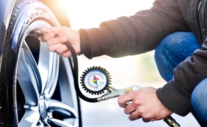 A person inflating a tire with a pump. The pump has a pressure gauge to show how inflated the tire is.