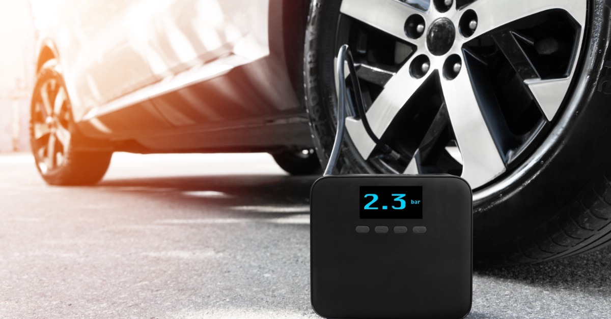 A car with a portable electric pump connected to the tire. The screen shows how inflated the tire is.