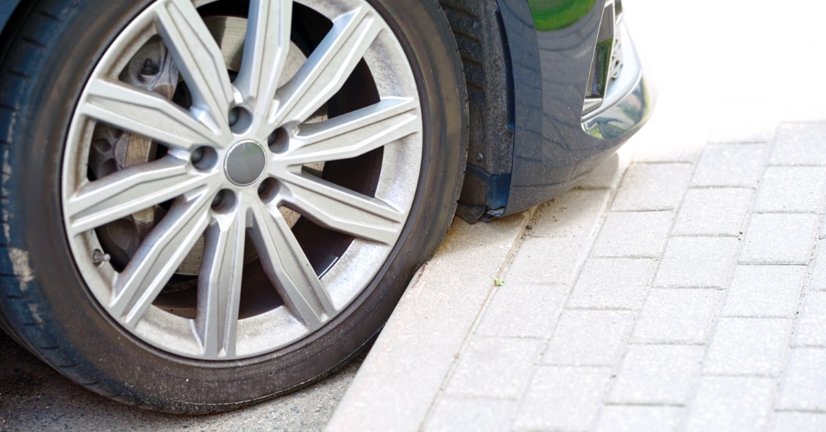A car parked too far up, forcing the tire into the curb. The tire now has a dent from the concrete's impact.