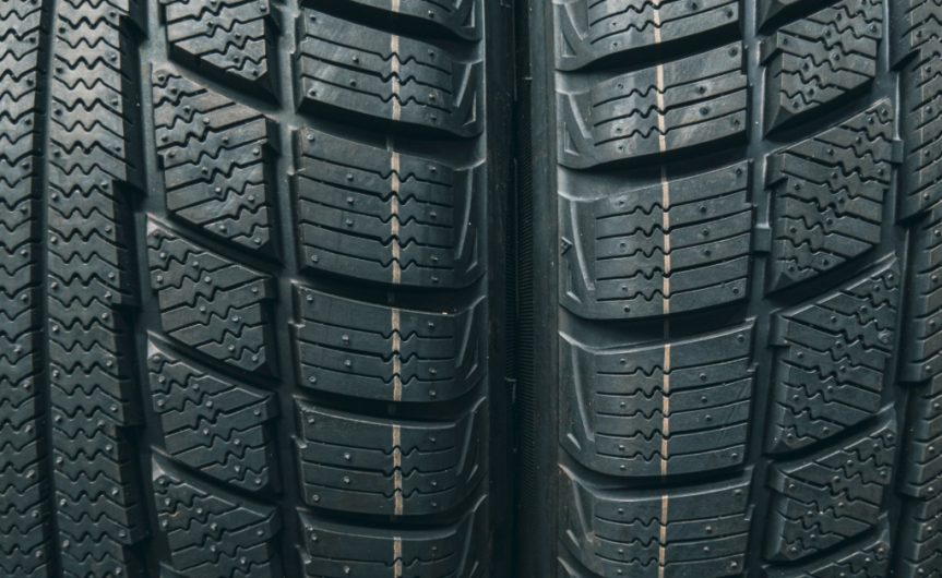 A close-up of two winter automotive tires side-by-side to show their deep grooves and asymmetrical tread block designs.