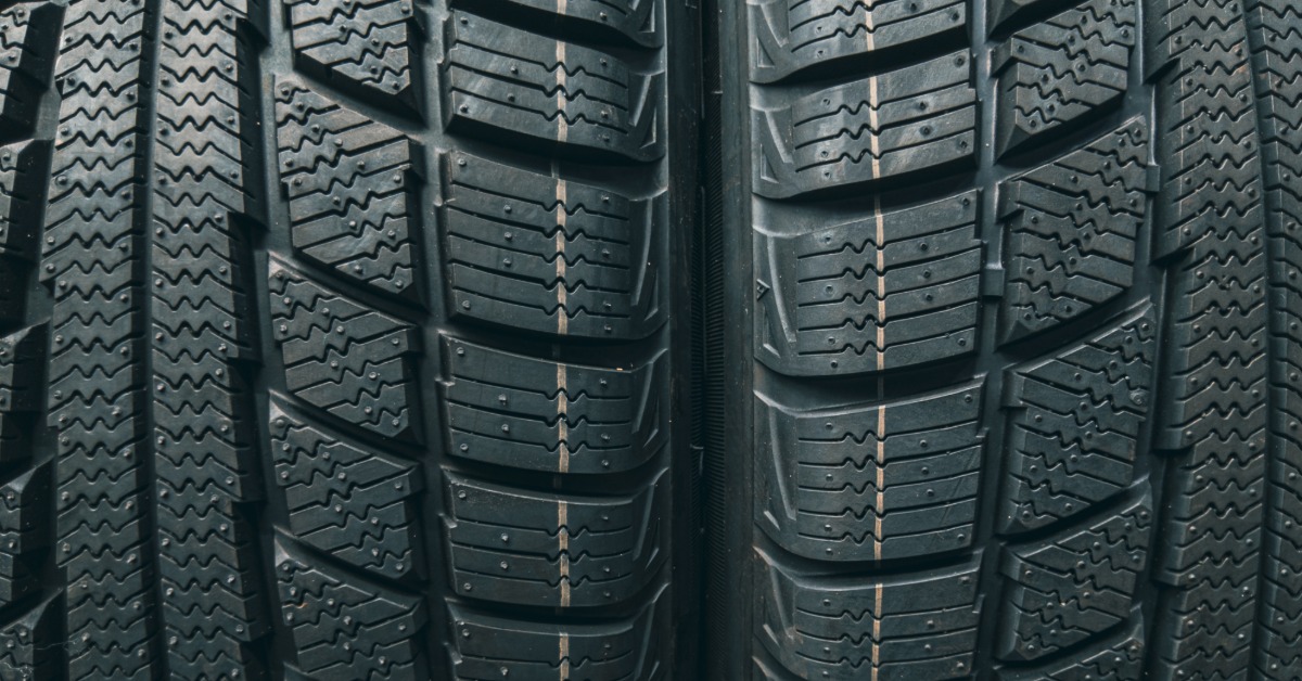 A close-up of two winter automotive tires side-by-side to show their deep grooves and asymmetrical tread block designs.
