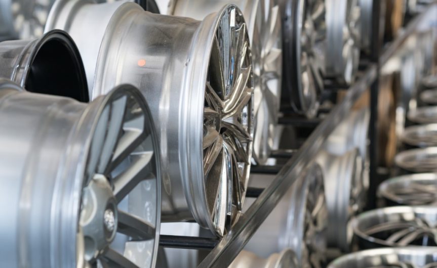 A close-up of a rack in a store with multiple levels of numerous alloy car wheels without tires of various designs.