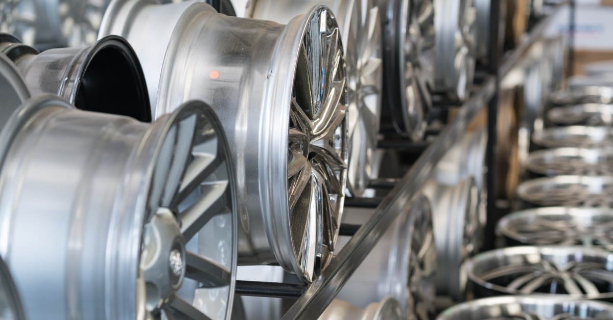 A close-up of a rack in a store with multiple levels of numerous alloy car wheels without tires of various designs.