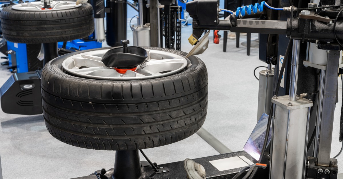 Two slightly used tires lie flat on two separate machines in an auto shop. The machine balances the tires.