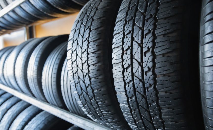 A close-up of several different types and sizes of tires resting in a row on a three-tier rack system.