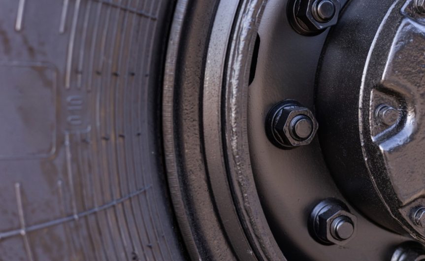 A close-up of a wheel hub and tire. The wheel hub has black lug nuts that are tightly secured.