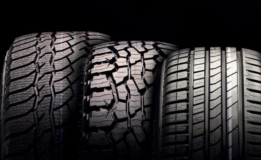 A close-up of three different tires, each of distinct sizes and tread patterns, against a black background.