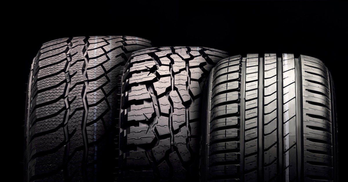 A close-up of three different tires, each of distinct sizes and tread patterns, against a black background.