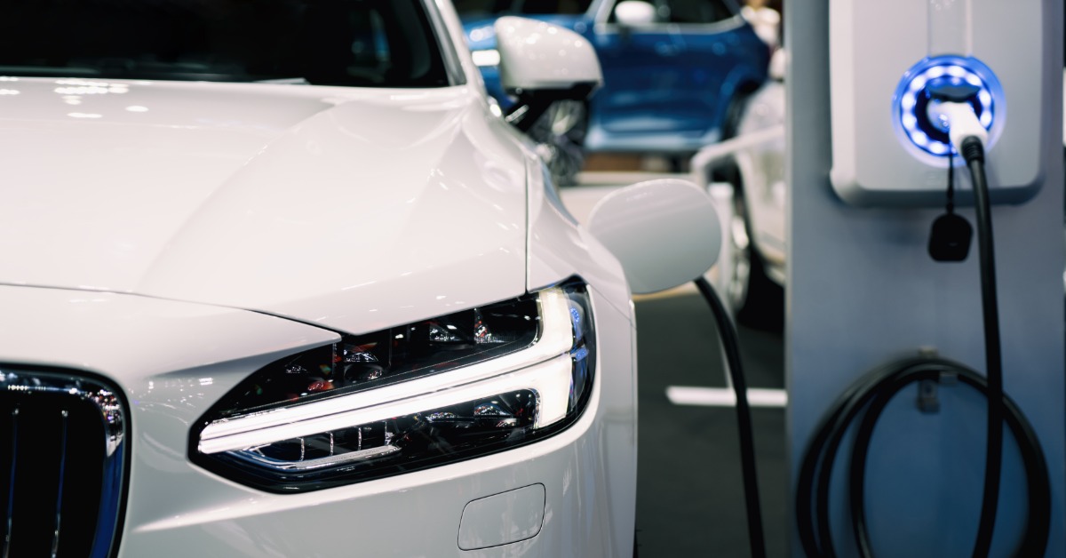 A white hybrid electric vehicle that is plugged into a charging battery. The vehicle is clean with no marks.