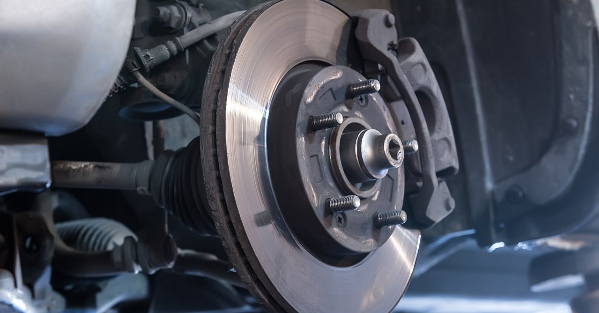 A close-up of an empty wheel position of a vehicle. Without the wheel, the brake disc and pad are visible.