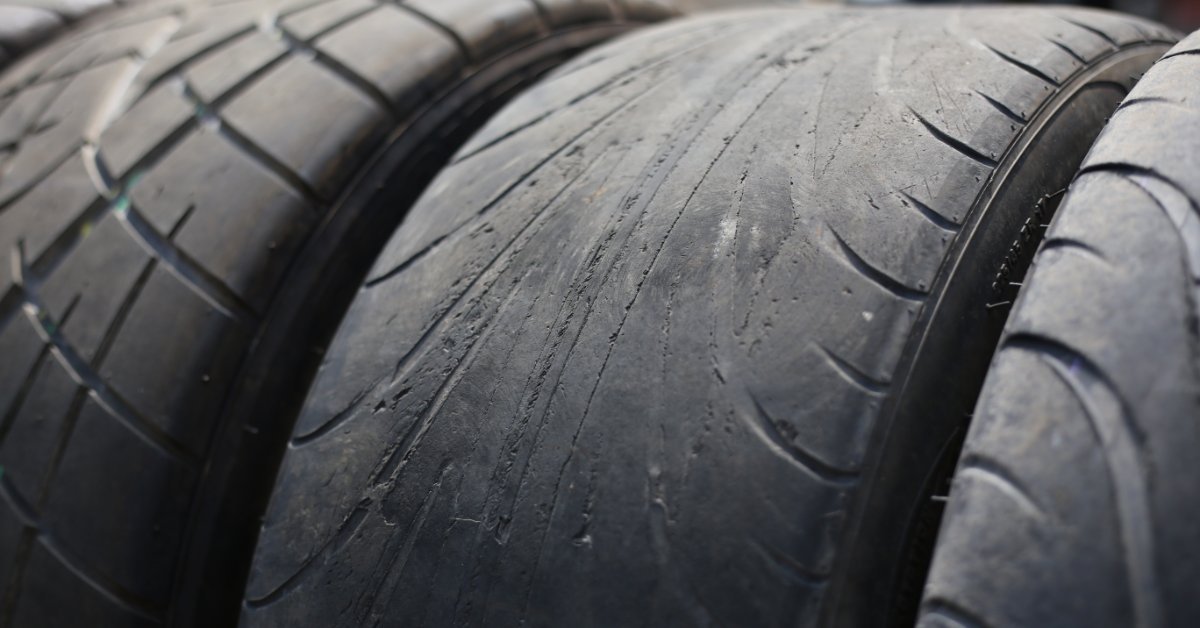 A few tires standing next to each other. The middle tire is extremely worn, with hardly any tread left on the rubber.