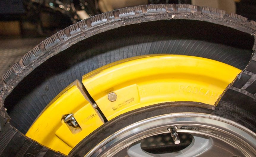 A run-flat tire with a portion of the sidewall cut out, exposing the technology that allows you to drive on a flat tire.