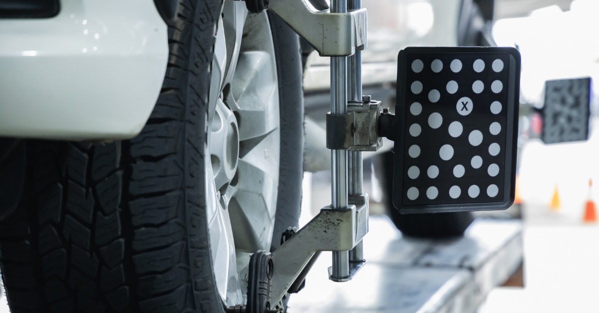 A close-up of a vehicle's tire with a wheel alignment target sensor clamped to the wheel. Another sensor is on the back tire, too.