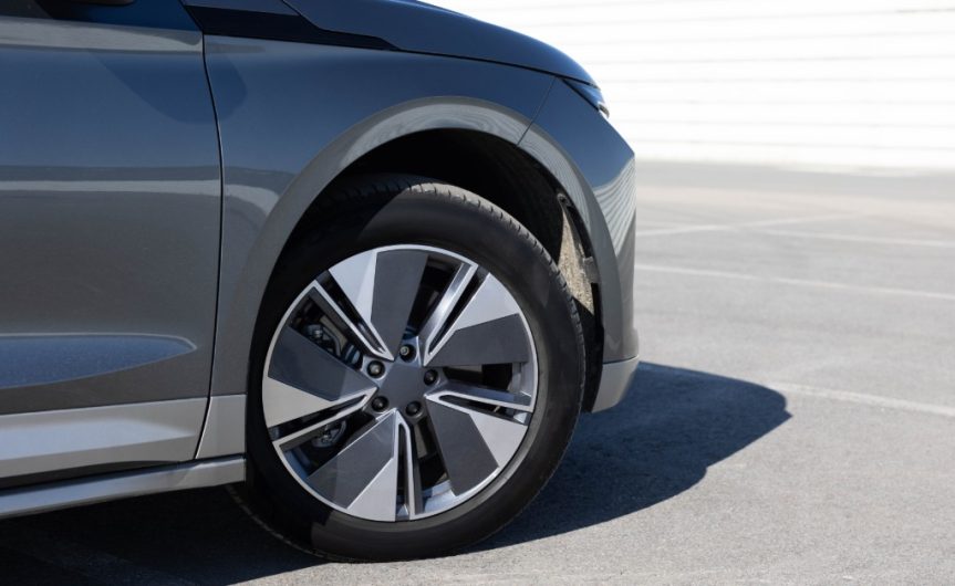The front of a grey SUV with the right side tire turned slightly outward. The car is in a parking lot.
