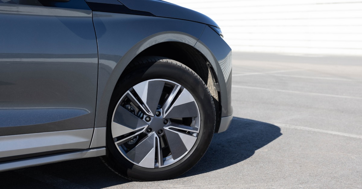 The front of a grey SUV with the right side tire turned slightly outward. The car is in a parking lot.