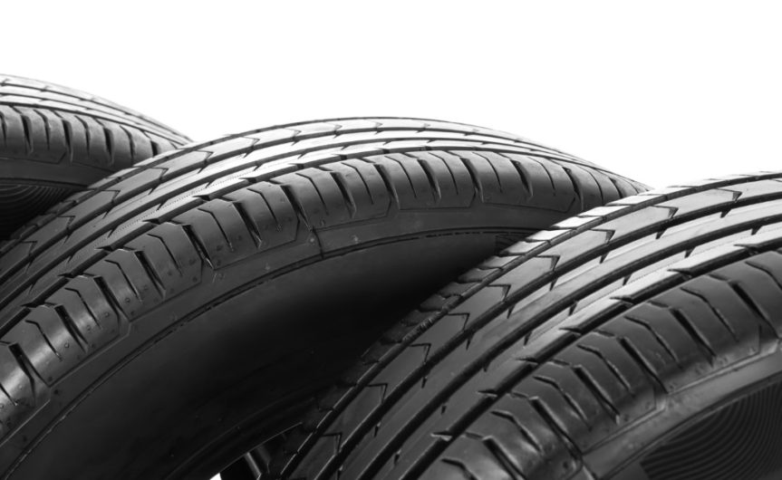 A close-up of three black car tires overlapping against a white background, showing tread patterns and sidewalls.