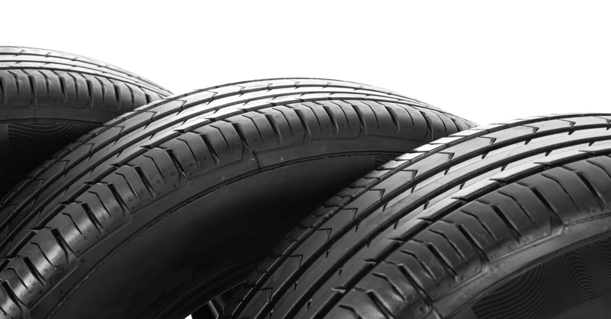 A close-up of three black car tires overlapping against a white background, showing tread patterns and sidewalls.